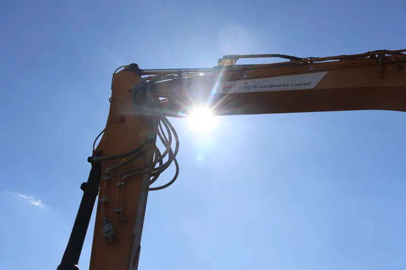 GE Groundworks branded excavator arm against the sun